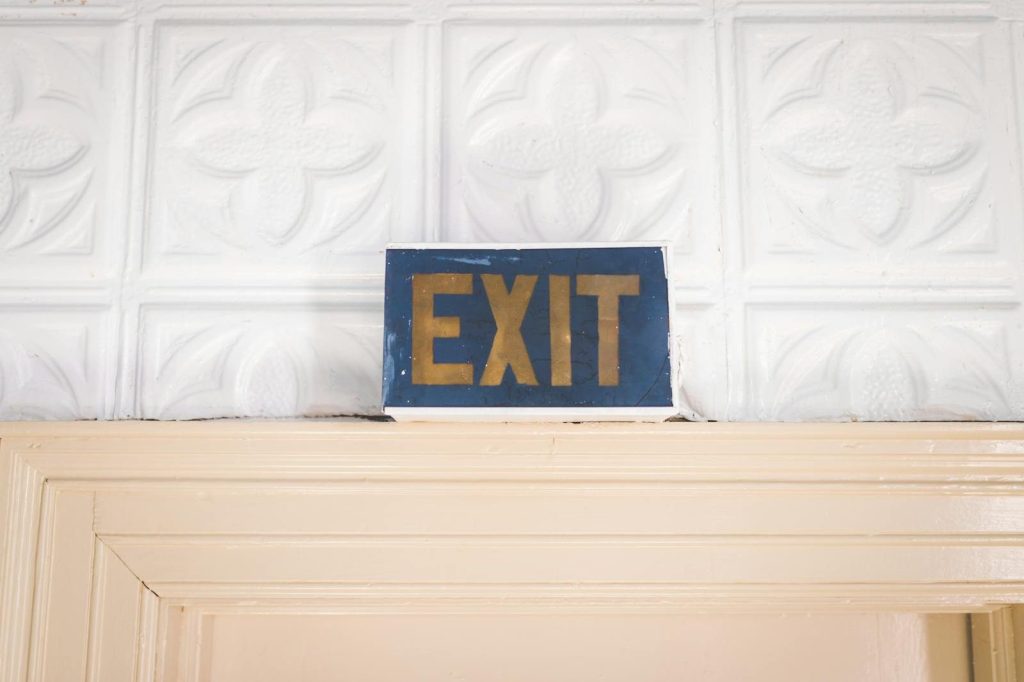 Old-fashioned exit sign with a retro feel above a wooden doorway indoors.