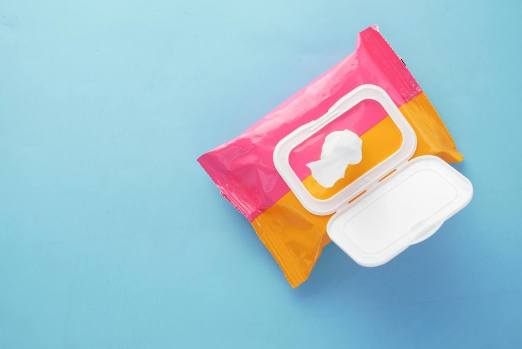 Brightly colored wet wipes package on a blue surface, symbolizing hygiene and cleanliness.