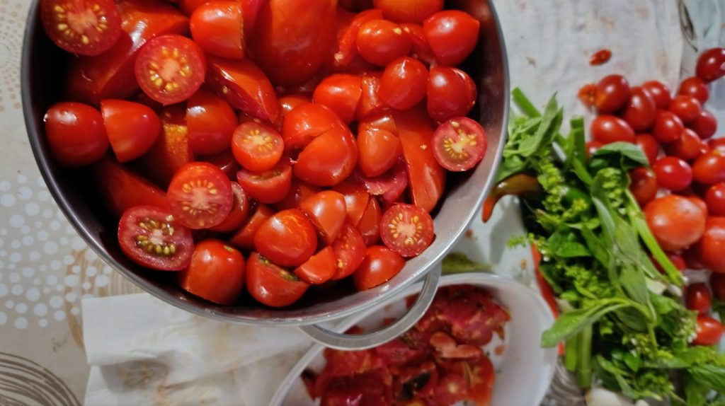 Fresh tomatoes being poured from a colander into a bowl.