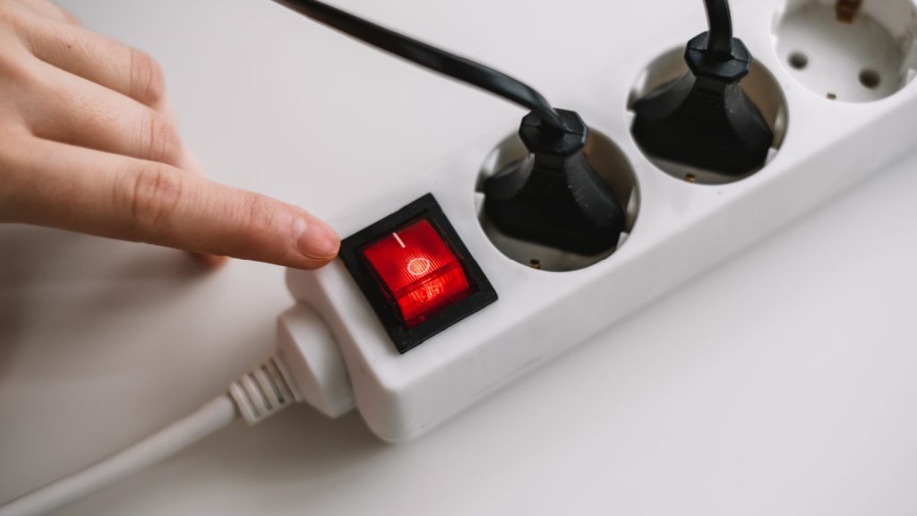 A woman turns on an electric surge protector. Protection of household appliances from electrical interference. Home safety