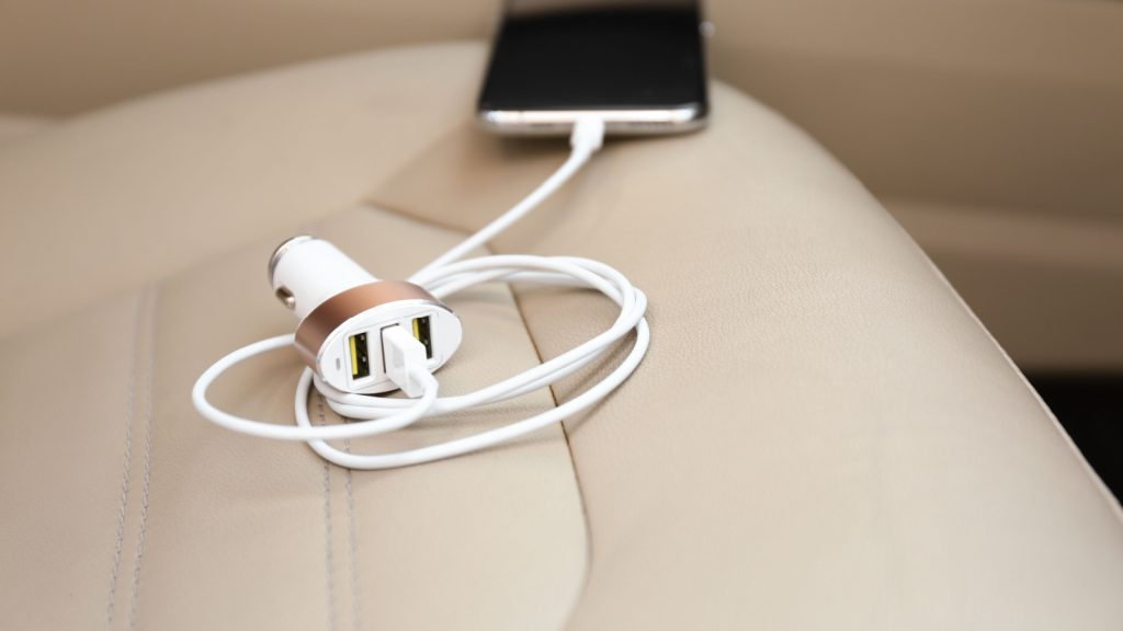 Adapter with connected charging cable and mobile phone in car, closeup