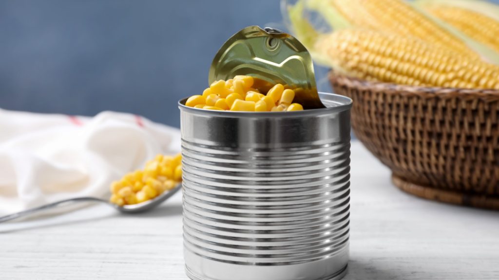 Can of preserved corn on white wooden table