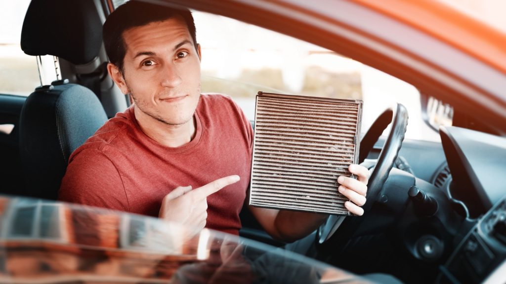 Man changes old polluted filter for the ventilation of the car interior. Dangerous particles of pollen, bacteria and viruses are collected in the air condition system