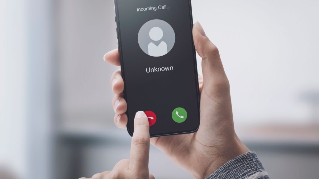 Woman receiving a call on her smartphone from an unknown number, malicious phone calls concept