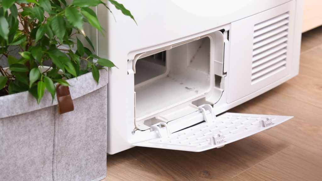Drying machine with a full filter of lint, hair, dust, wool after the drying cycle of towels, bed linen. White drying machine. Dirty dryer filters.