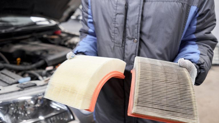 New and old dirty automotive engine air filter in the hands of an auto mechanic. Auto repair concept.