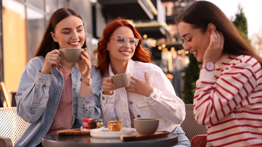 Happy friends drinking coffee in outdoor cafe