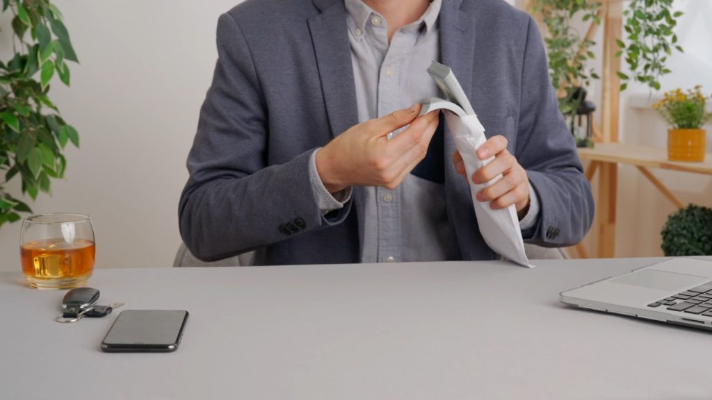 Business man sits at office desk takes out of pocket envelope with money and counts cash . Private commercial and business payments.