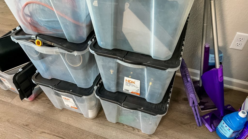 Castle Rock, Colorado, USA-April 11, 2023-A collection of clear plastic storage bins with black lids stacked against a wall used for organizing and packing during a moving process Some bins contain