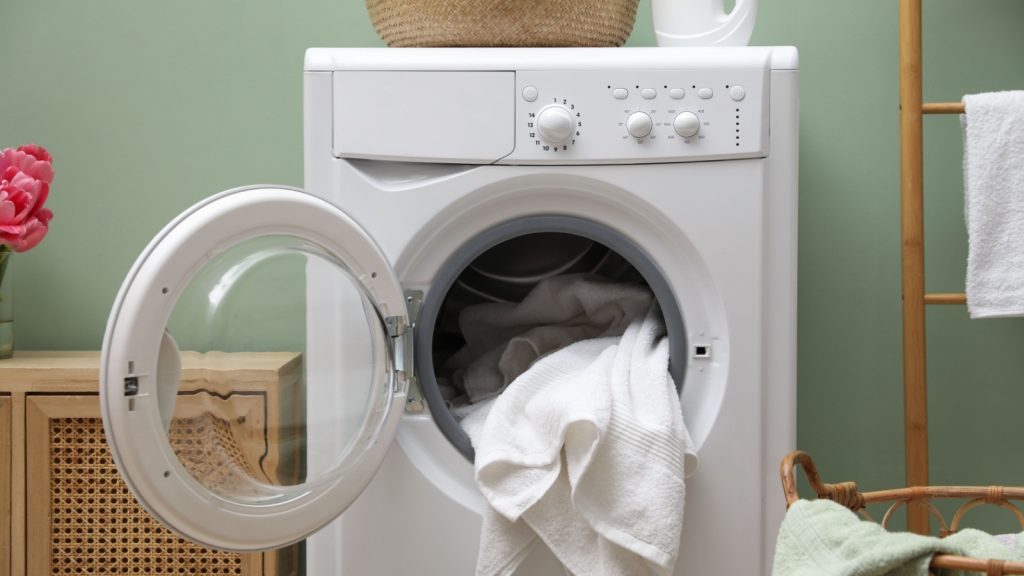 Washing machine with towels near green wall indoors