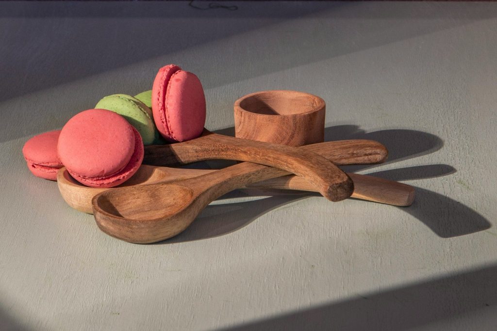Macarons rest with wooden spoons and a small cup.