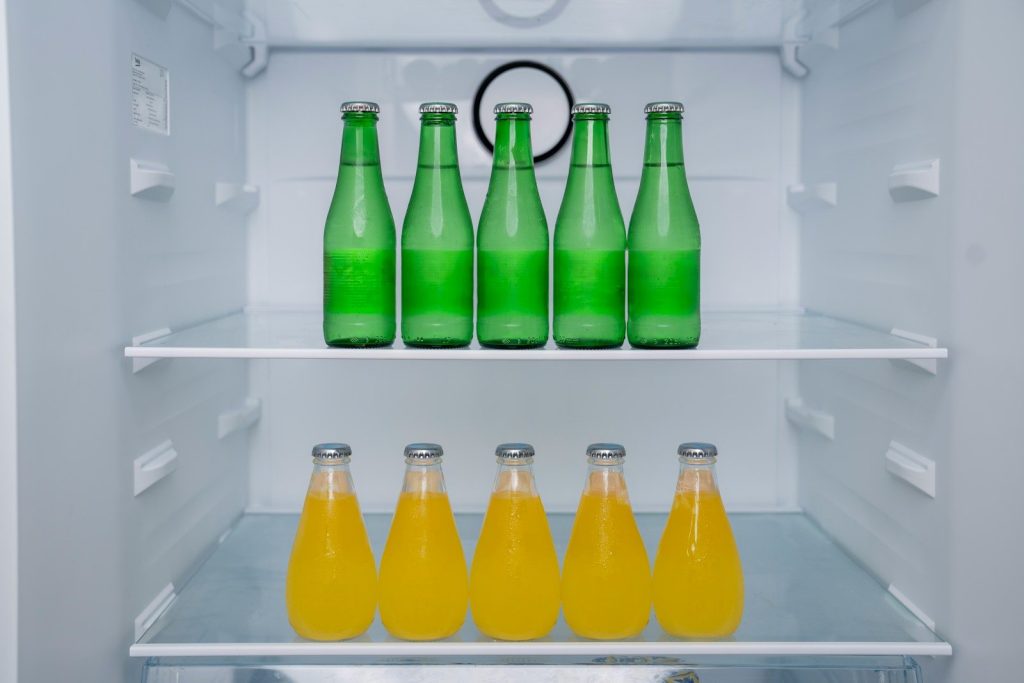 A refrigerator filled with lots of green and yellow bottles