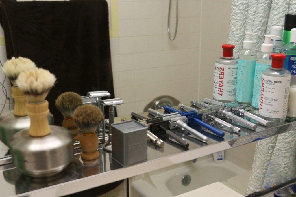 Collection of shaving brushes and razors on shelf