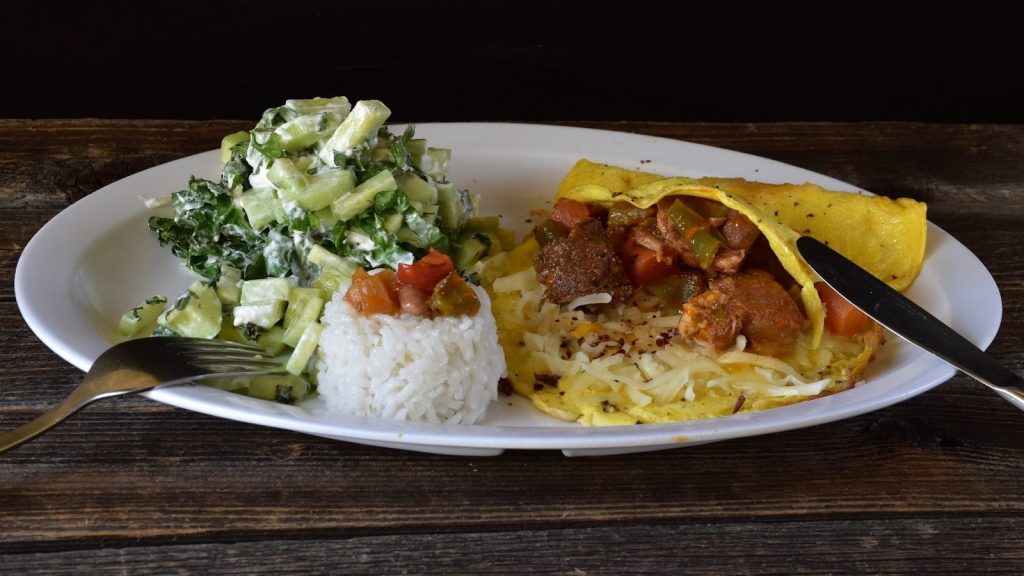 Delicious meal featuring rice, salad, and an omelet.
