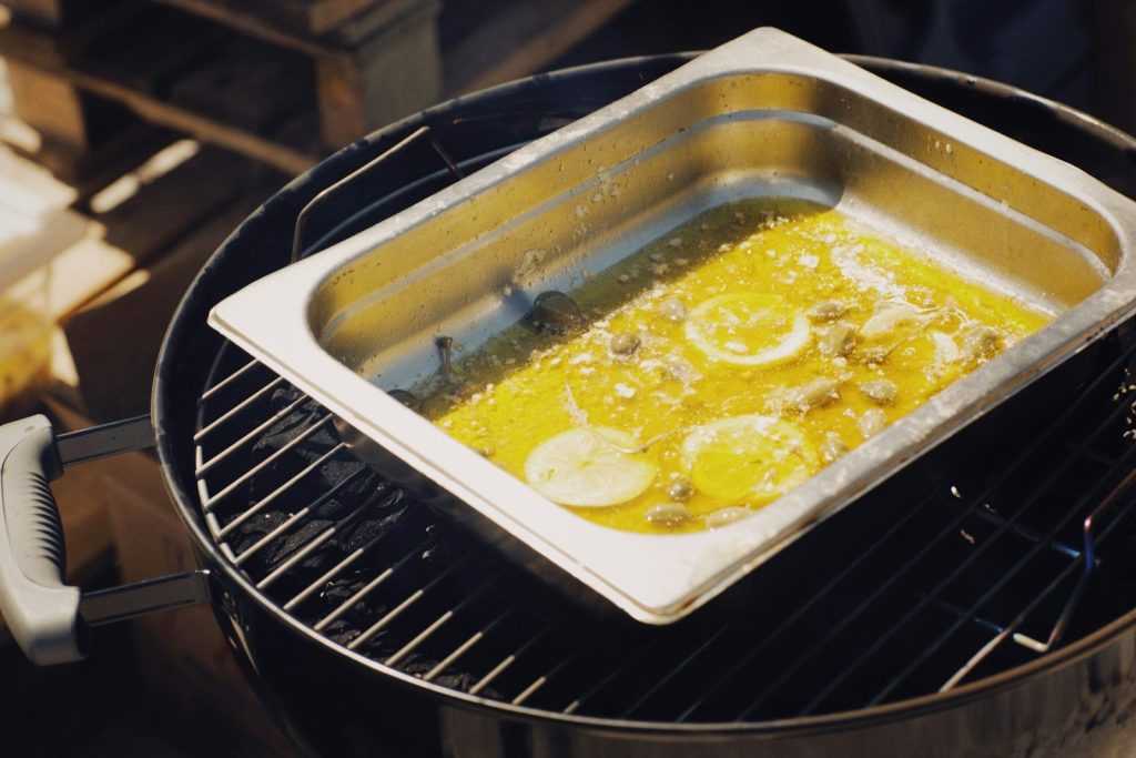 a pan filled with food sitting on top of a grill