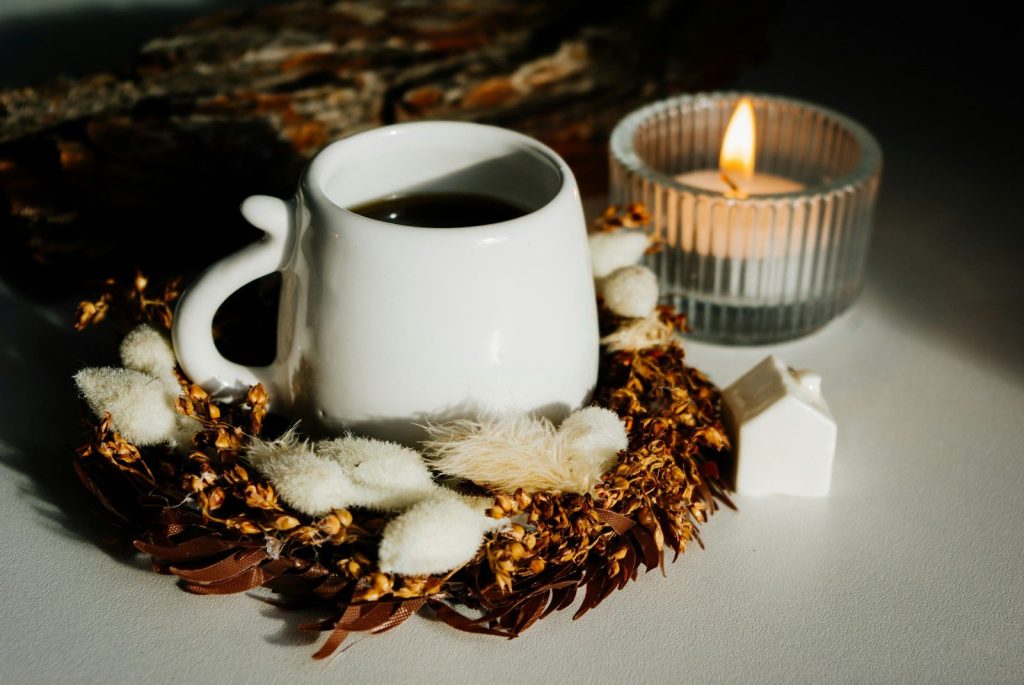 a cup of coffee sitting next to a candle