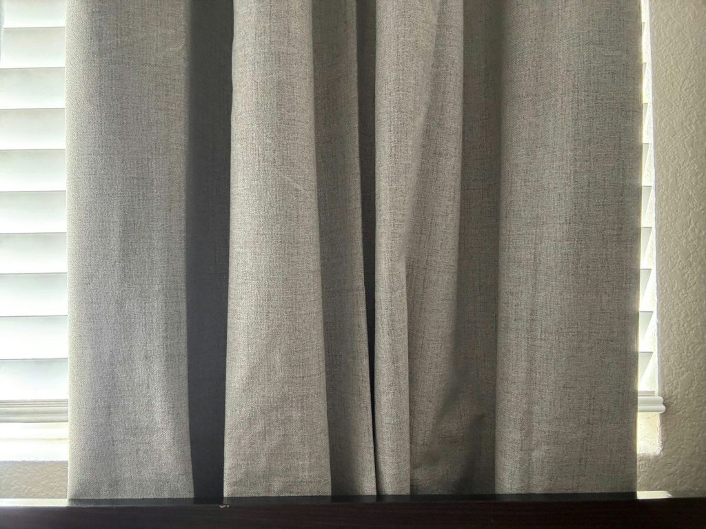 Gray curtains hang in front of a window.
