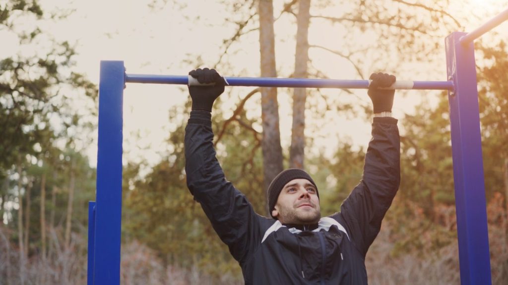 Man exercising on a pull-up bar outdoors
