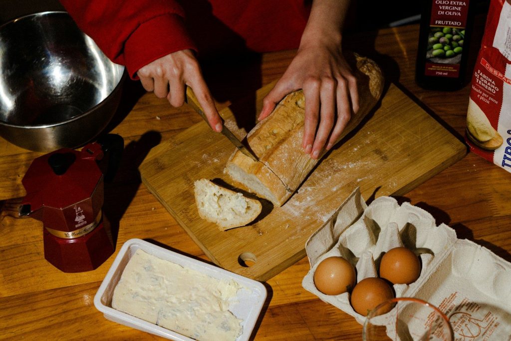 a person cutting bread on a cutting board