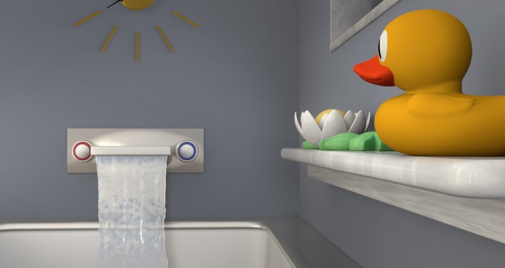 A yellow rubber duck sitting on a ledge in a bathroom