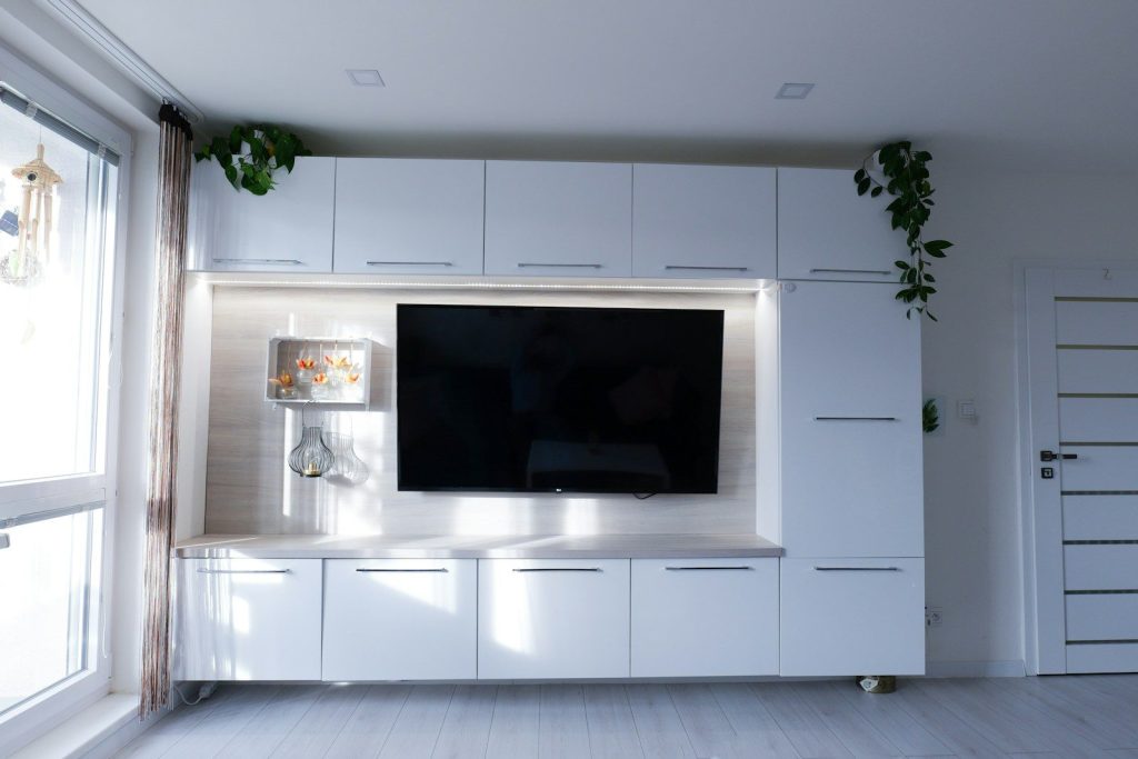 Modern white entertainment center with a large television.