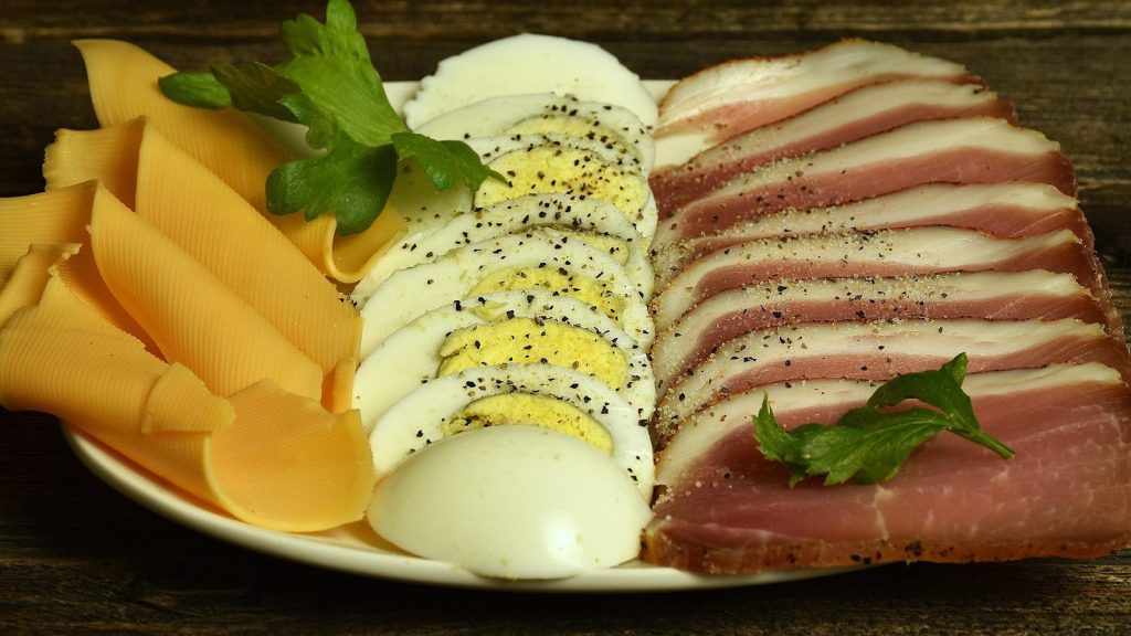A white plate topped with meat and cheese