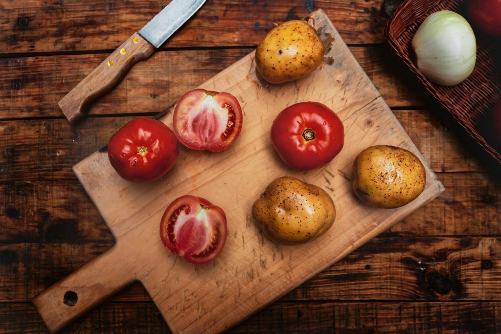 a cutting board topped with tomatoes and potatoes