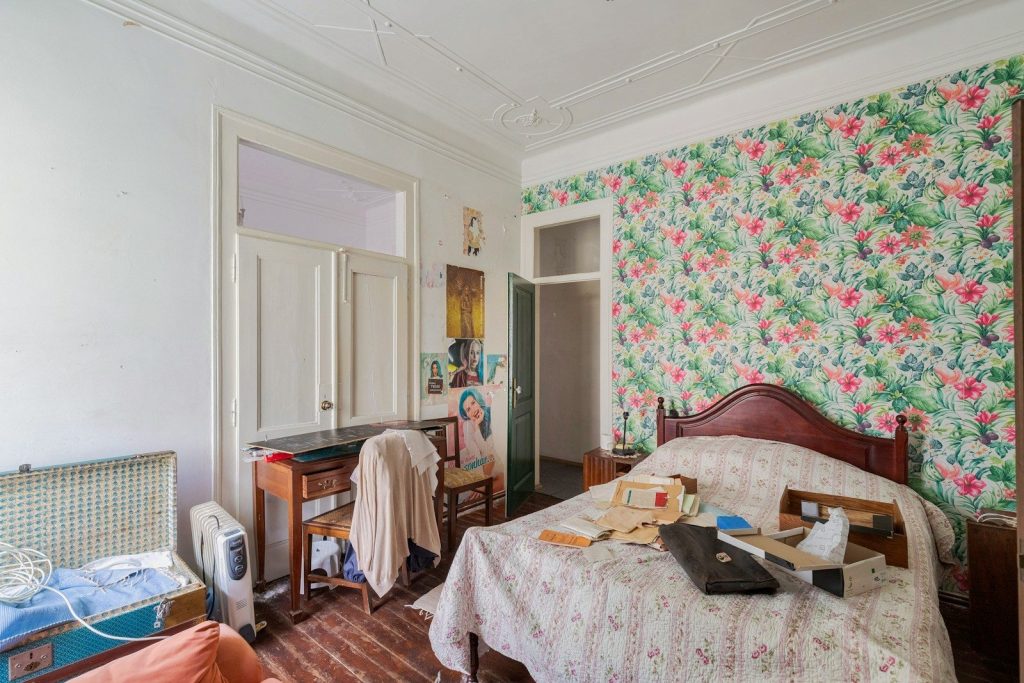 A bedroom with floral wallpaper and a wooden bed.