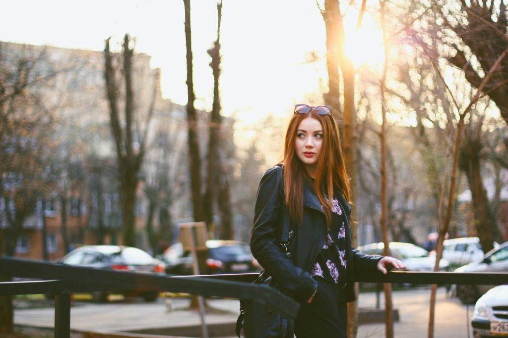woman in black jacket standing near trees during daytime