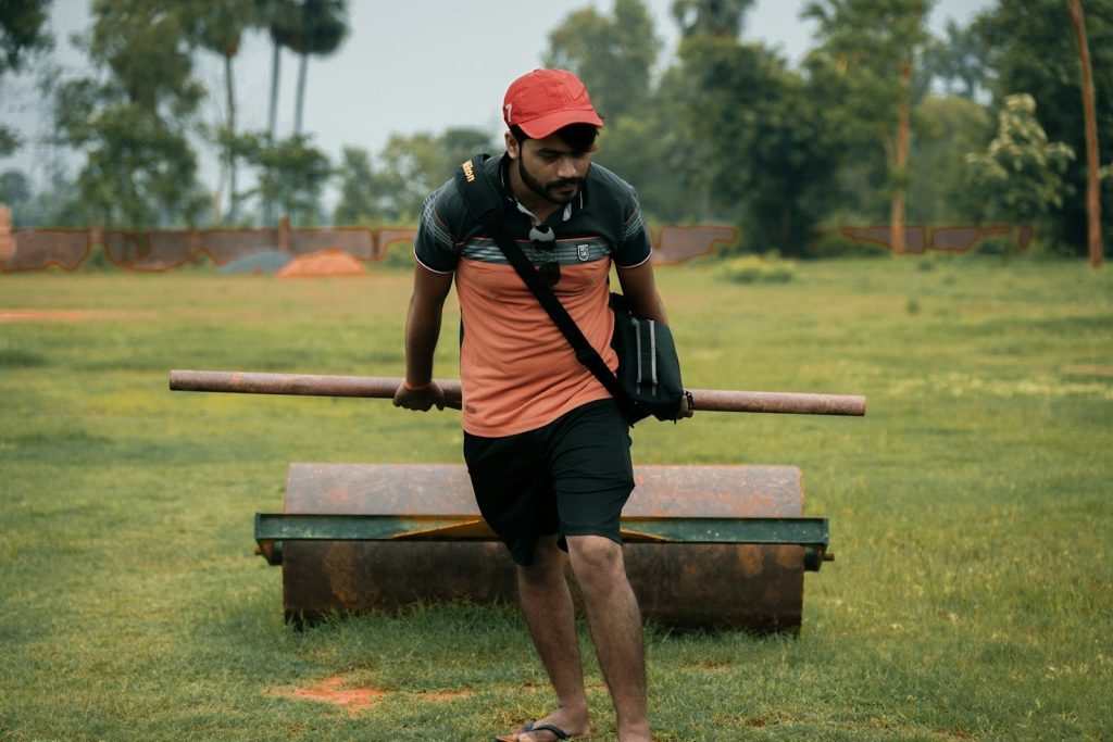 man in black and red t-shirt and black shorts sitting on brown wooden bench during
