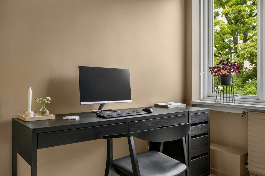 A desk with a computer on top of it next to a window
