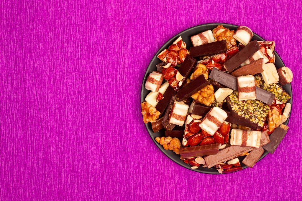 A dark bowl filled with assorted chocolates and nuts.