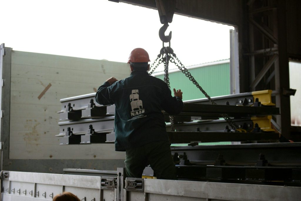 a man in a green shirt is lifting a piece of metal