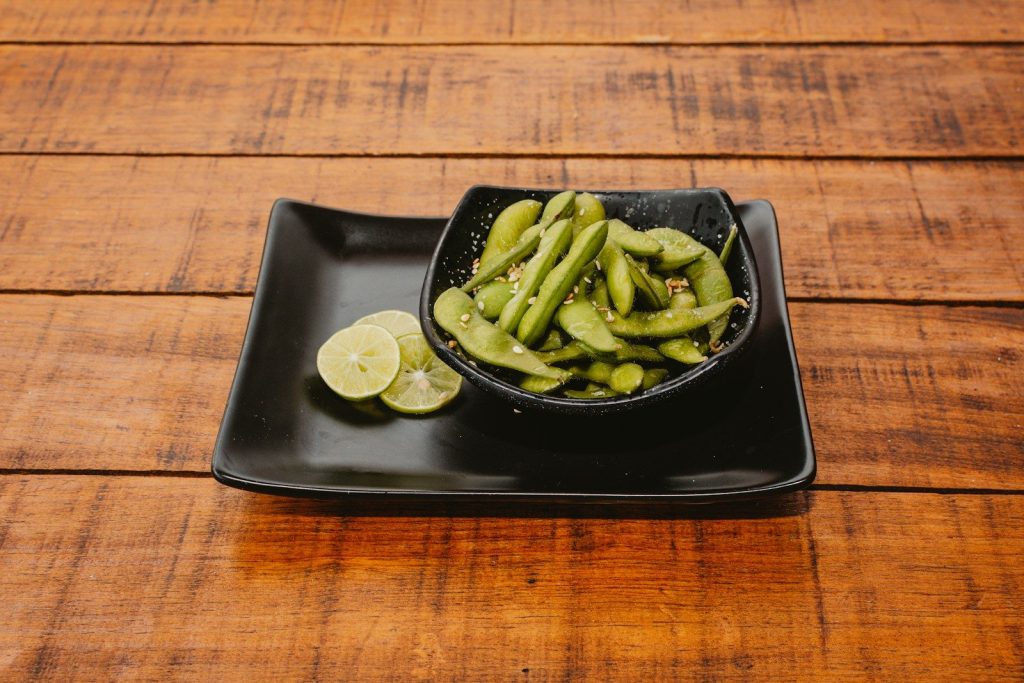 A black plate topped with green beans and sliced lemons