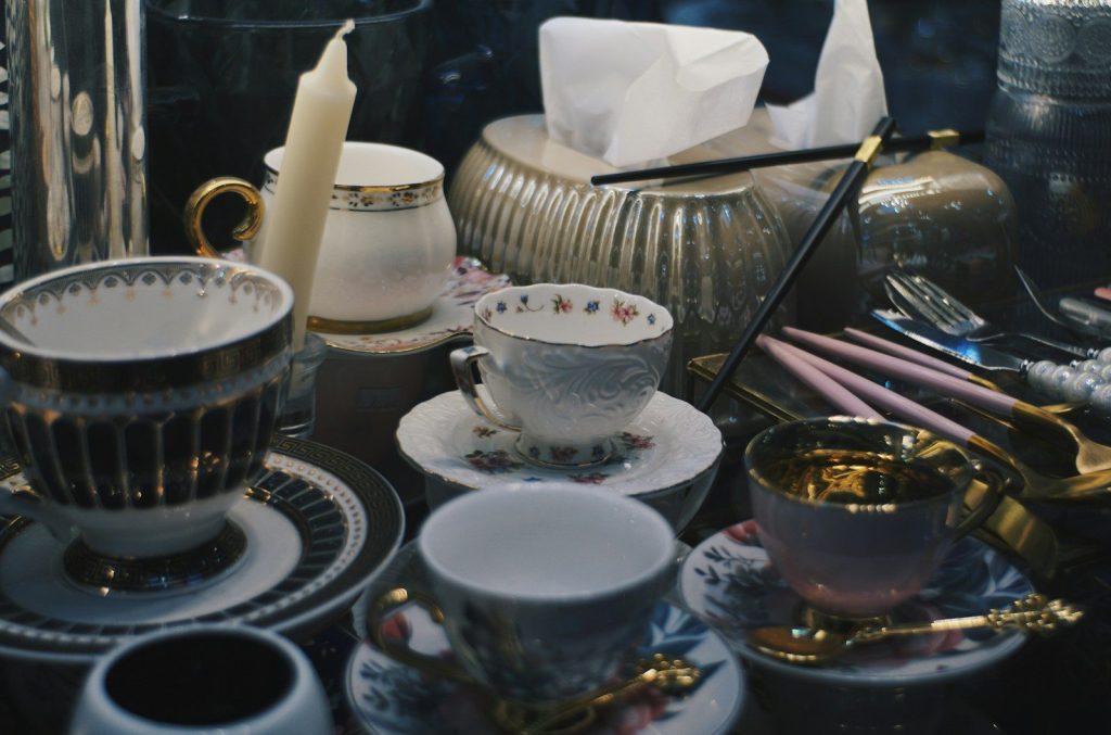 Collection of antique teacups and saucers with candle.