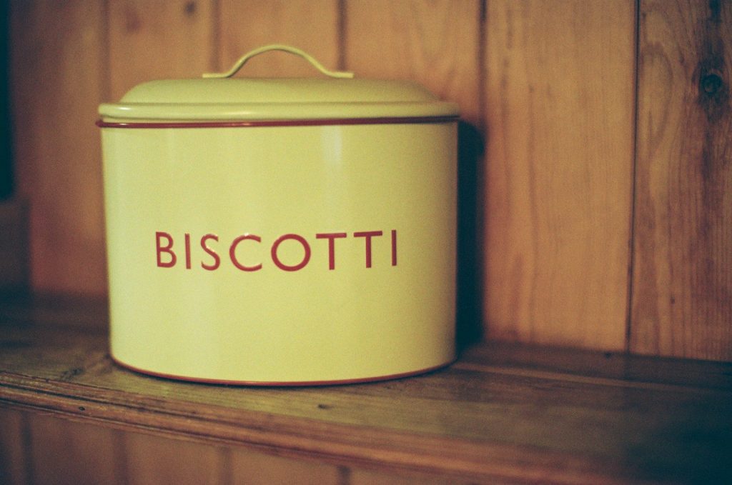 A vintage biscotti tin on a wooden shelf.