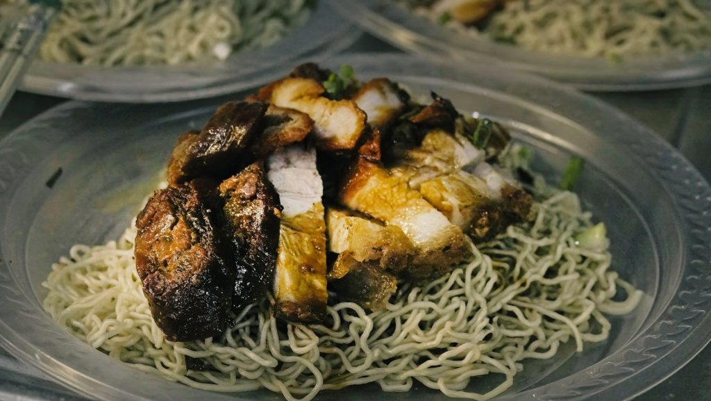 Roasted pork belly served over egg noodles