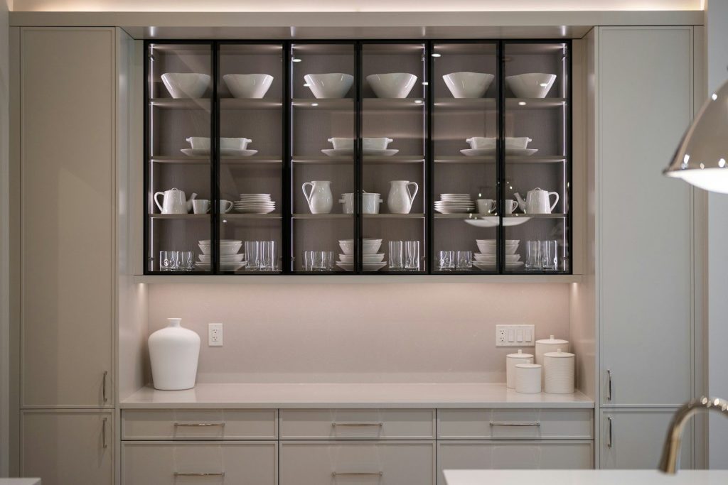 Elegant kitchen display cabinet showcasing white dinnerware and glasses.