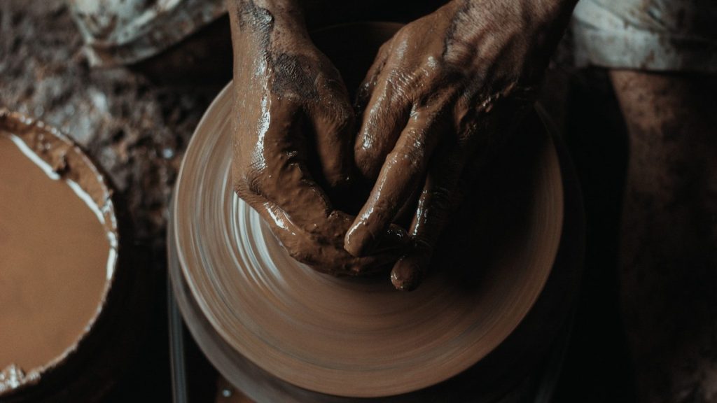 a potter's hands on a potter's wheel making clay