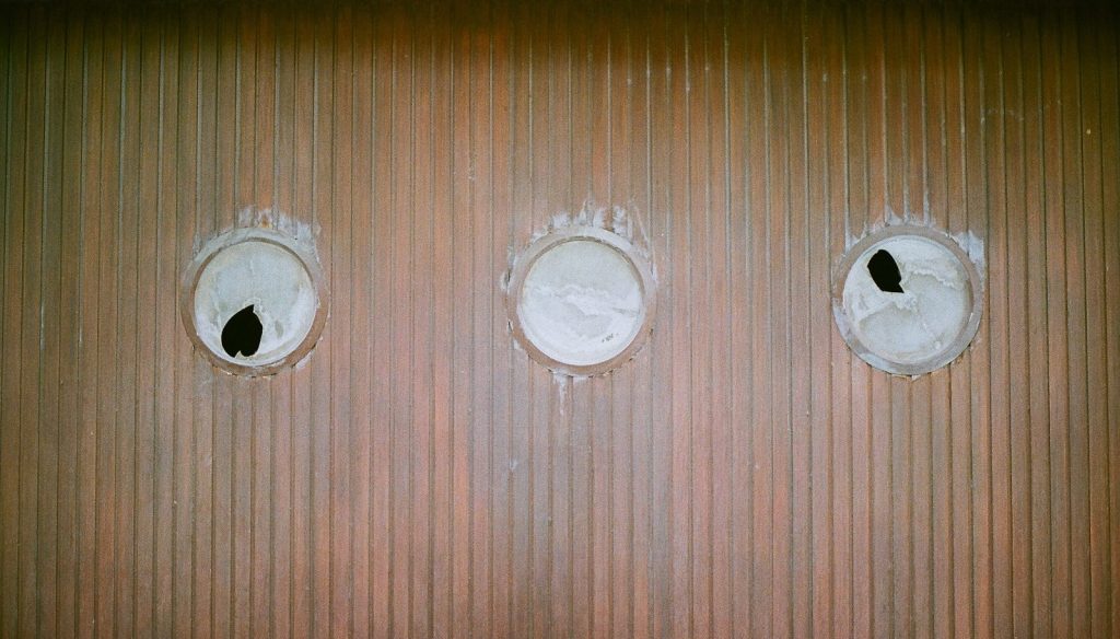 Three circular holes in a textured wall.
