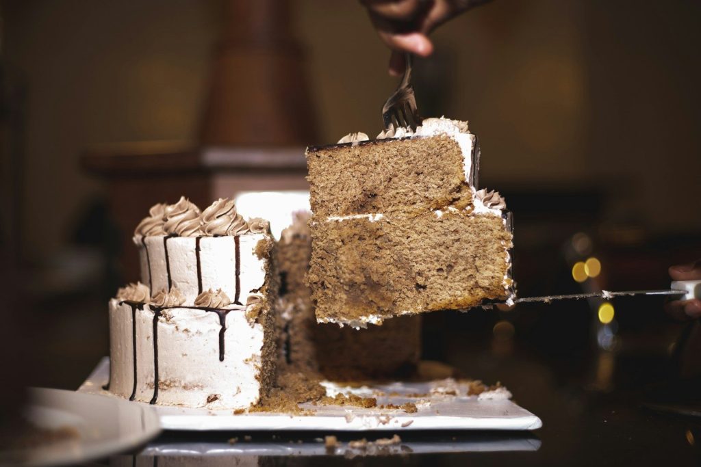person holding brown and white cake