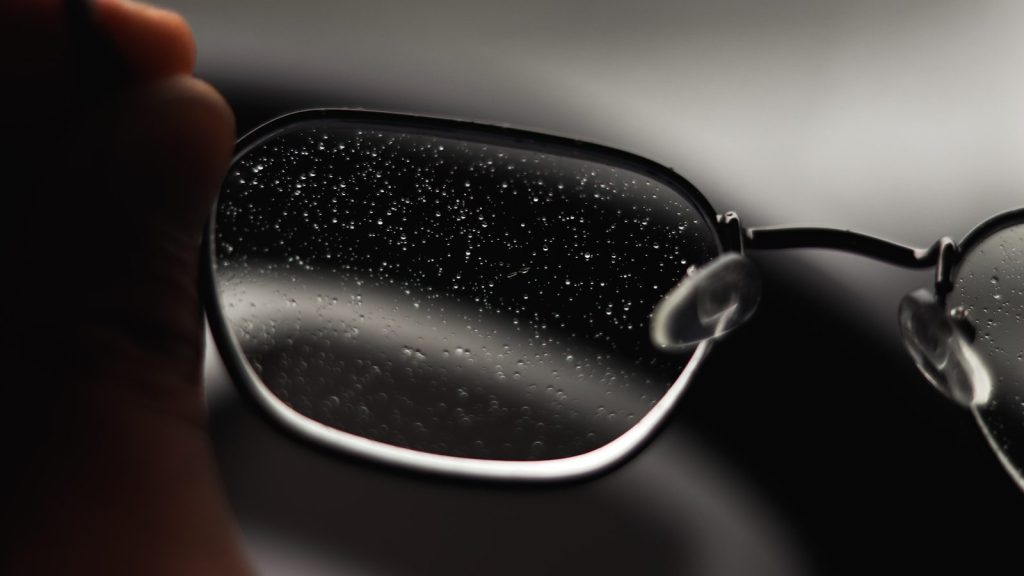 A person holding a pair of glasses in their hand