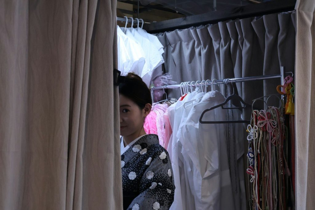 A woman looking through the curtains of a closet