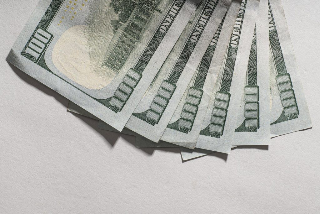 Several hundred dollar bills fanned out on a white surface