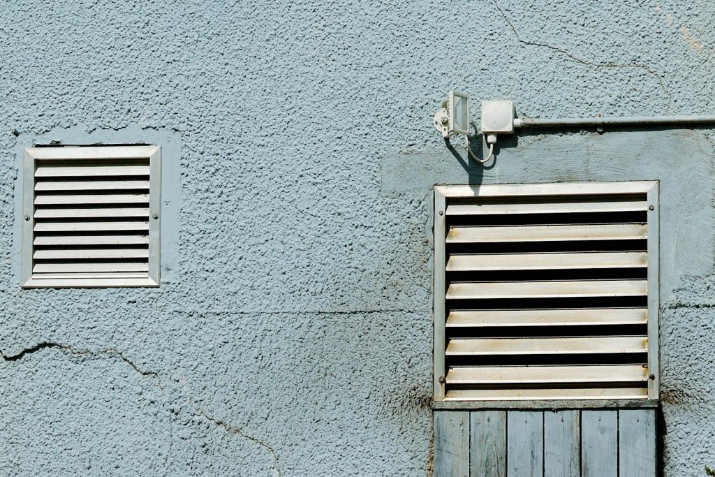 Two vents are set into a textured blue wall.
