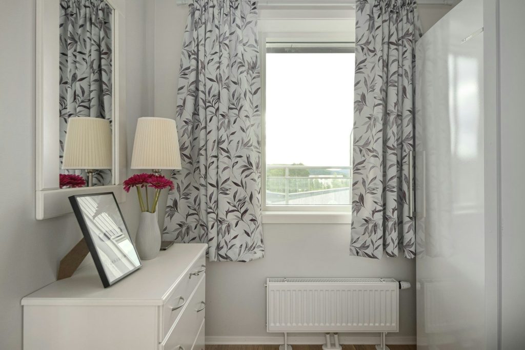 A bedroom with a bed, dresser, mirror and window