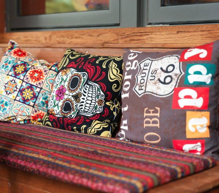 A wooden bench with a bunch of pillows on it