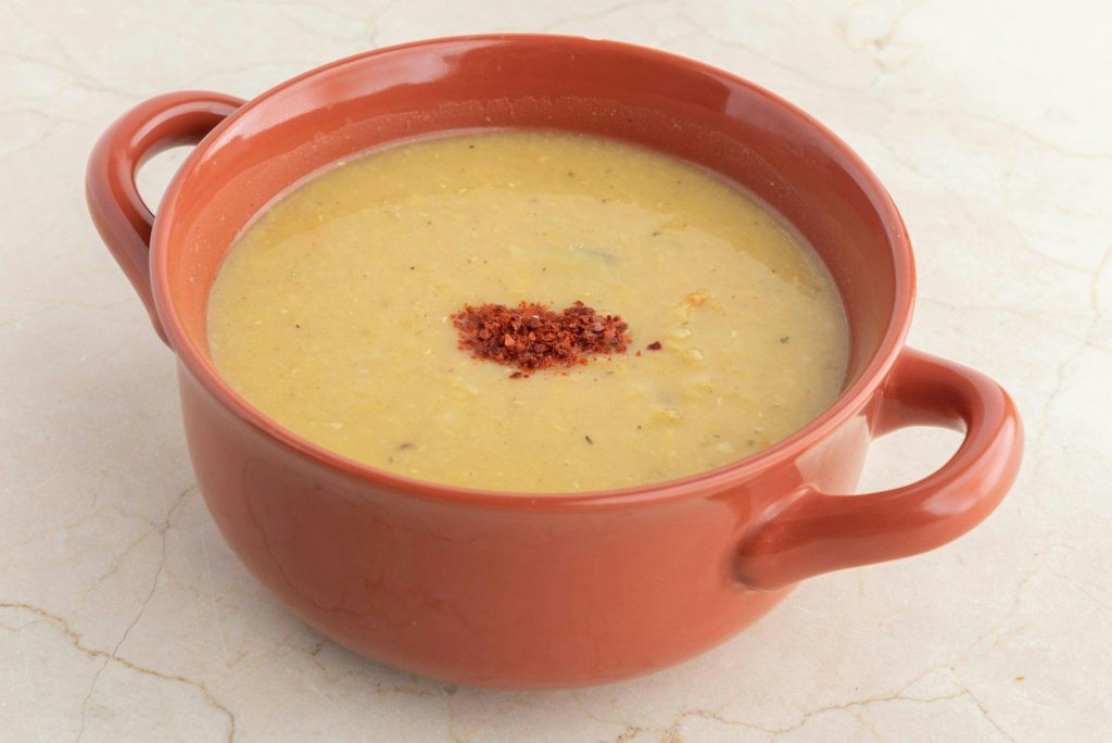 A red bowl filled with soup on top of a white counter