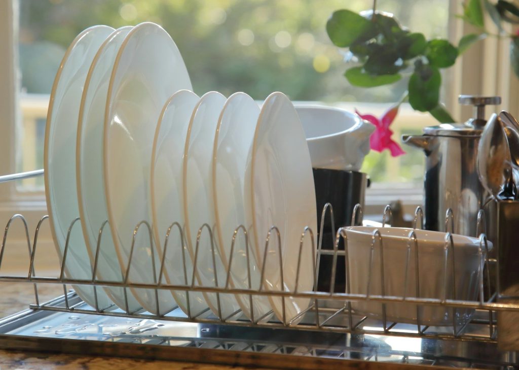 Clean white plates drying in a metal dish rack.