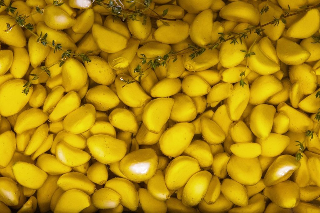 a pile of yellow mangoes with green leaves on top